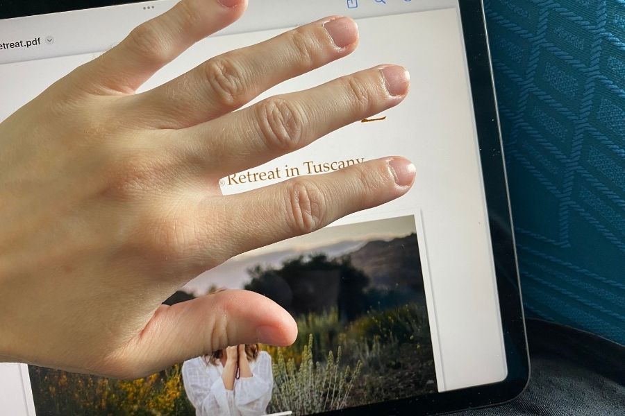 eine Hand verdeckt eine (noch geheime) Retreat-Broschüre auf dem Bildschirm