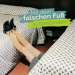 Eine Frau liegt unter einem Bett. Es ragen nur ihre Beine hervor. Darüber der Schriftzug: "Mit dem falschen Fuß aufgestanden?"