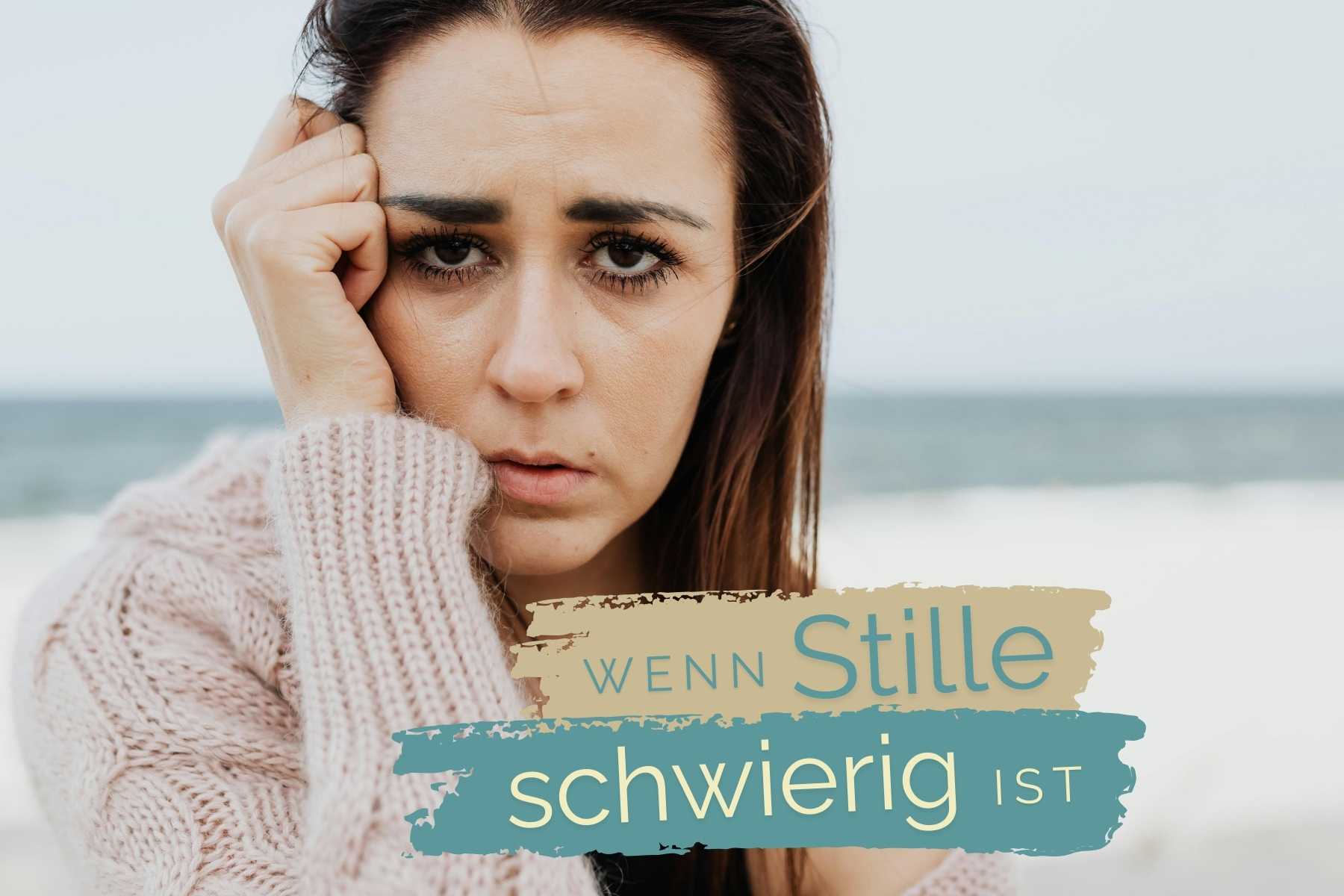 Nahaufnahme einer dunkelhaarigen Frau am Strand. Sie hat eine Hand am Kopf und sieht erschöpft aus. Darunter der Schriftzug "Wenn Stille schwierig ist"