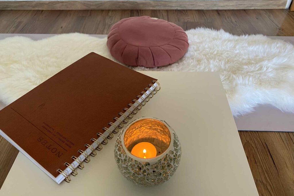 Meditationsecke mit Sitzkissen, Kerze und Journal